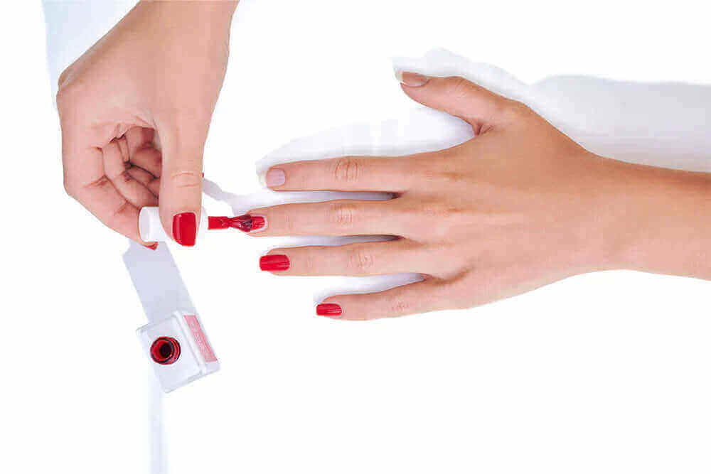 Hände werden lackiert mit rotem UV Nagellack von Nailtime während des Lackieren-Prozesses.