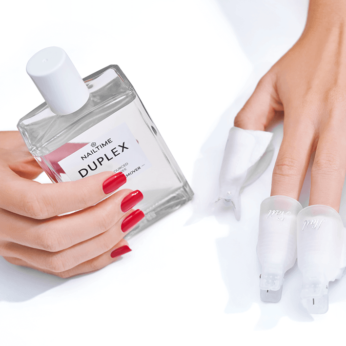 Hand holding DUPLEX EXPRESS NAIL POLISH REMOVER with red nails and UV nail polish on fingers.