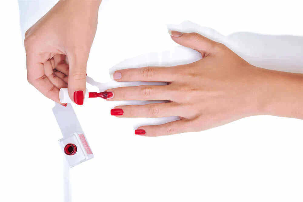 Person putting red Nagellack on nails with a stylish Nailtime bottle.