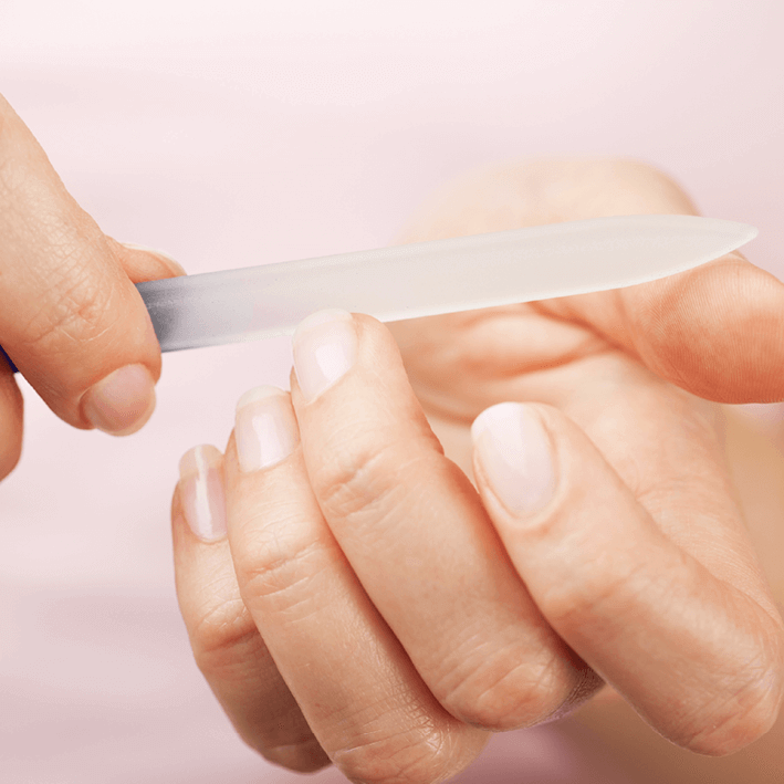Person using NAILTIME glass file on nails for smooth, healthy appearance with a gentle touch.